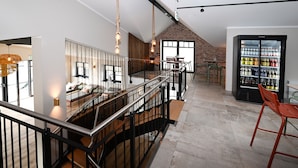 Une cuisine moderne avec un plafond haut, un mur en briques apparentes et un grand réfrigérateur rempli de boissons.