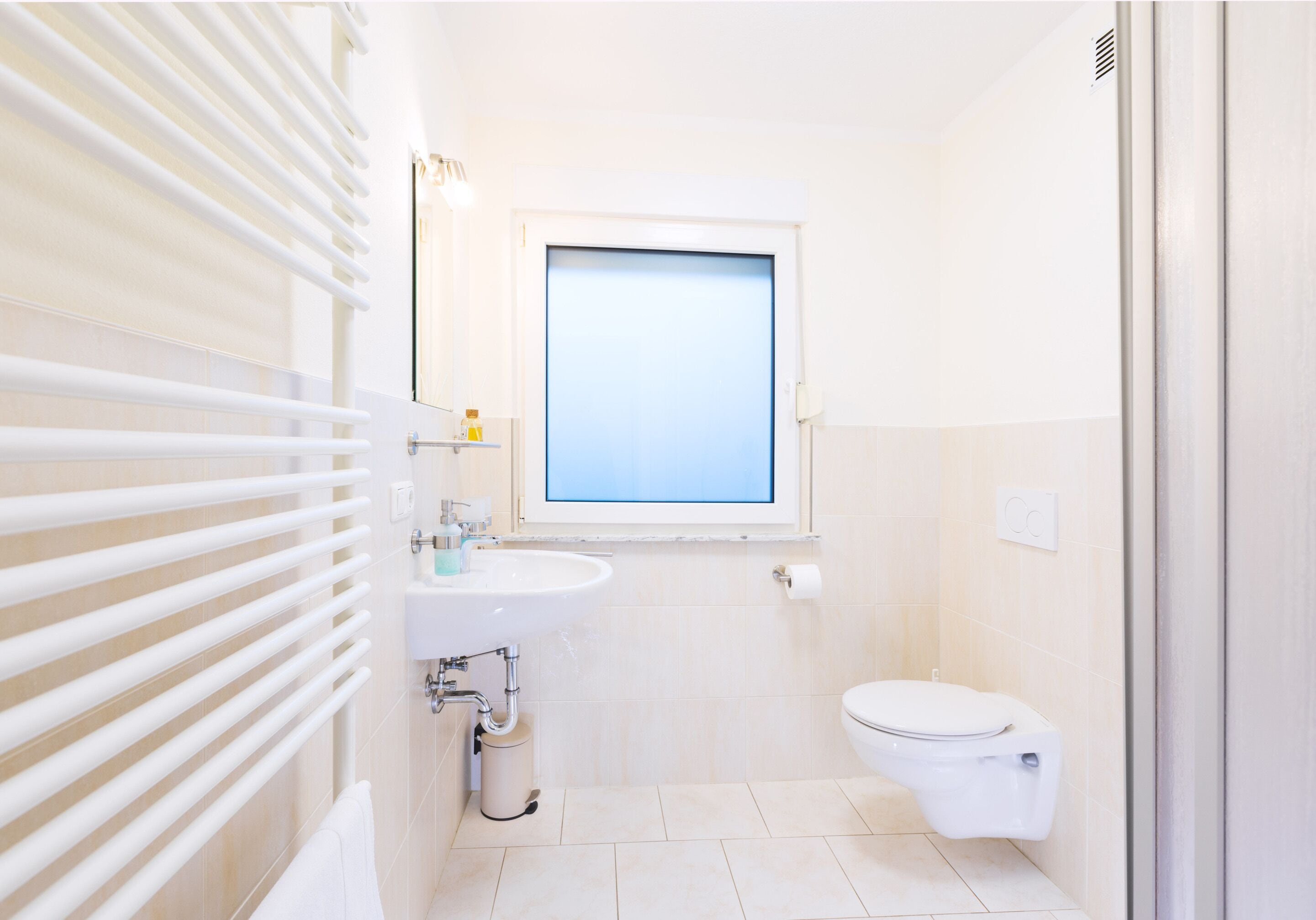 A small, modern bathroom with a toilet, sink, and window.