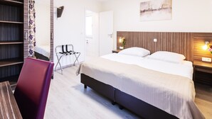 A hotel room with a bed, a desk, a chair, and a wardrobe. - Pension Altes Backhaus (Herzogenaurach)