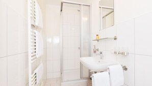 A modern bathroom with a glass shower enclosure, a white sink, and a mirror above the sink. - Pension Altes Backhaus (Herzogenaurach)