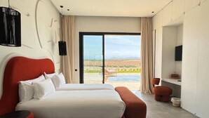 Ein modernes Hotelzimmer mit einem großen Bett, einem Schreibtisch und Blick auf einen Pool und die Landschaft.