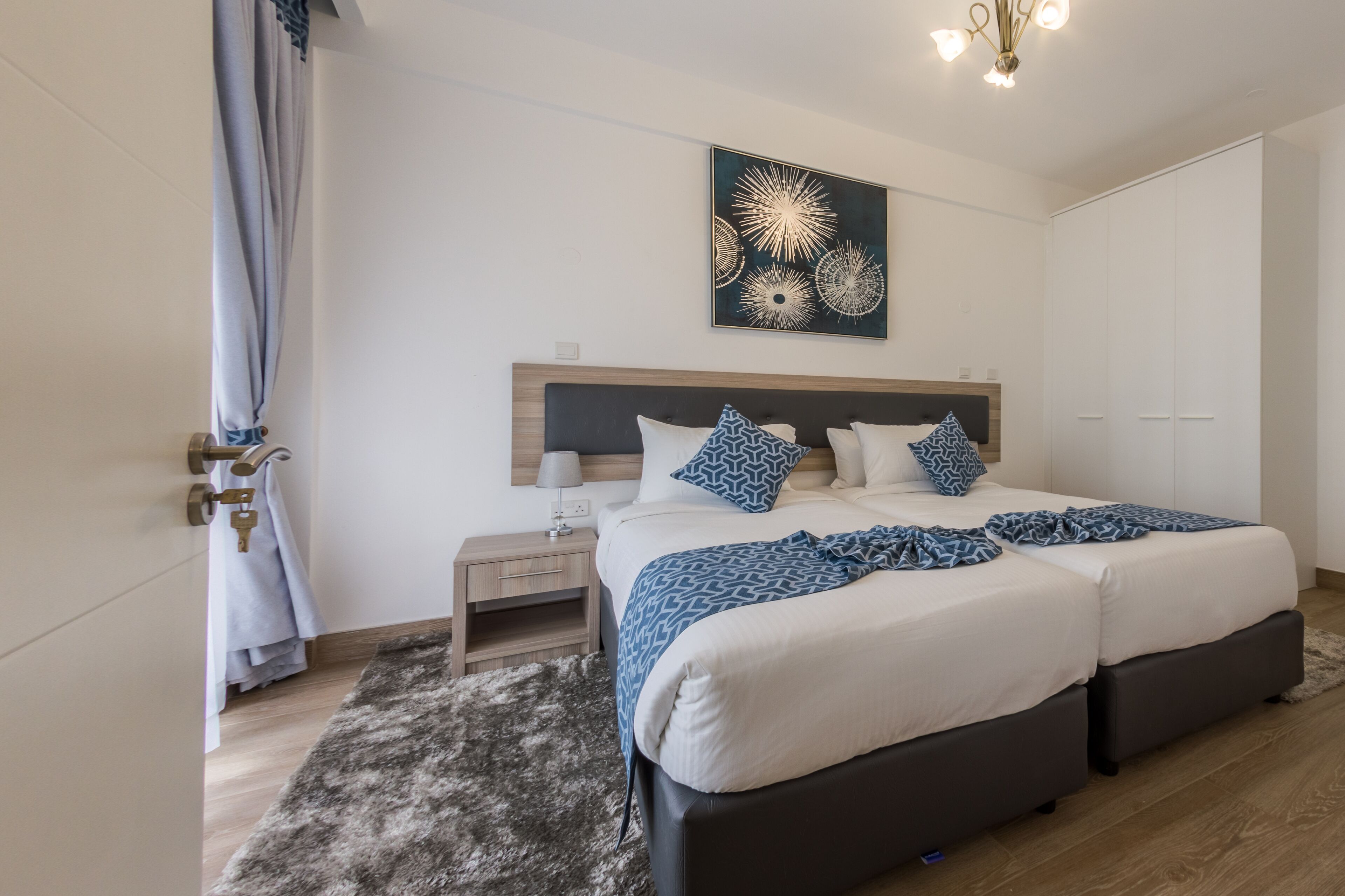 A modern bedroom with a double bed, a nightstand, a wall-mounted artwork, and a wardrobe.