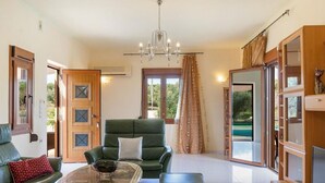 A spacious living room with a green sofa set, a coffee table, and a chandelier. - Villa Roula 3BR Seaview Villa in Chania (Chania)