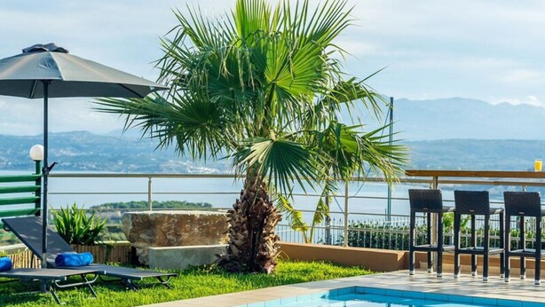 A pool area with a palm tree, lounge chairs, and a view of the mountains. - Villa Roula 3BR Seaview Villa in Chania (Chania)