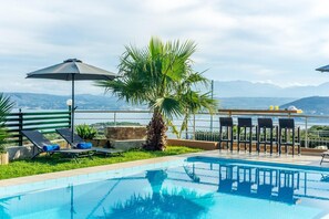 A pool area with lounge chairs, a palm tree, and a view of the mountains. - Villa Roula 3BR Seaview Villa in Chania (Chania)