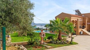 A modern building with a pool, palm trees, and a clear sky. - Villa Roula 3BR Seaview Villa in Chania (Chania)
