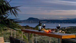 A terrace with a table set for a meal, overlooking a scenic landscape with a body of water and hills. - Villa Roula 3BR Seaview Villa in Chania (Chania)