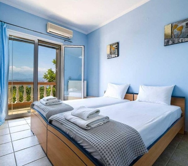 A hotel room with two beds, a balcony, and a large window. - Villa Roula With Private Pool (Chania)