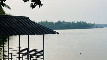 A wooden dock with a metal roof overlooking a calm body of water.