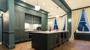 A kitchen with dark cabinetry, a central island, and a herringbone-patterned floor. - Hob Hurst - Spacious 4 Bed Apt Hot Tub & Parking (Buxton)