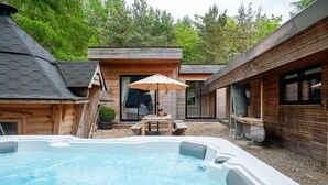 A hot tub in a backyard with wooden cabins and a patio area. - Twenty One -  a lodge that sleeps 12 guests  in 6 bedrooms (Richmond)