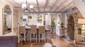 A cozy kitchen with a central island, white cabinetry, and a stone wall. - Sun Hill Cottage -  a cottage that sleeps 6 guests  in 3 bedrooms (Leyburn)