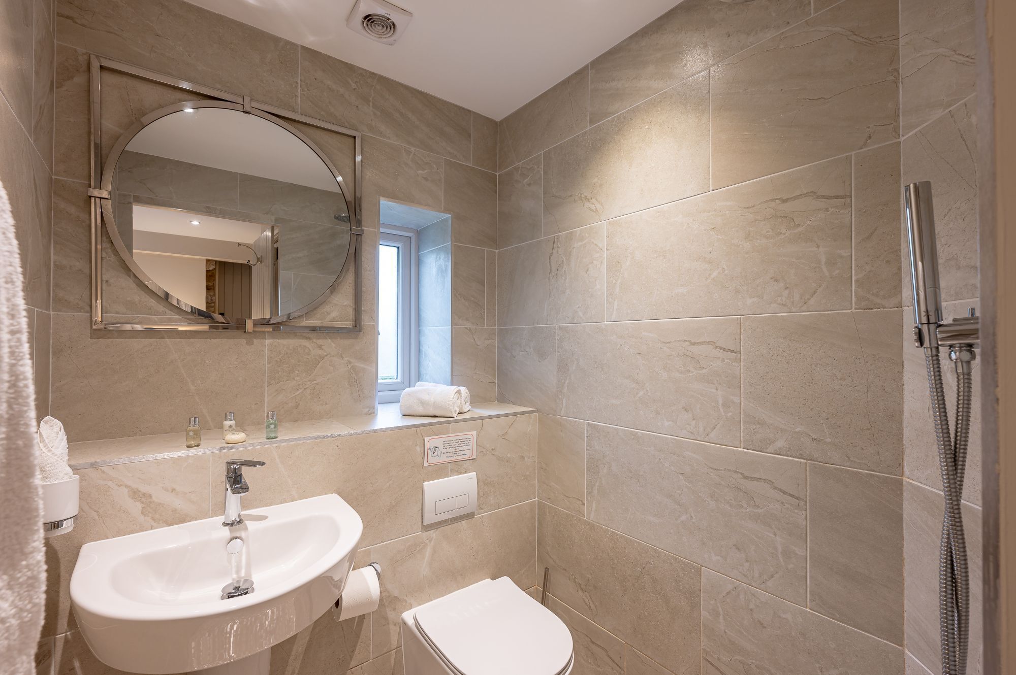 Een moderne badkamer met een wastafel, spiegel en douche.
