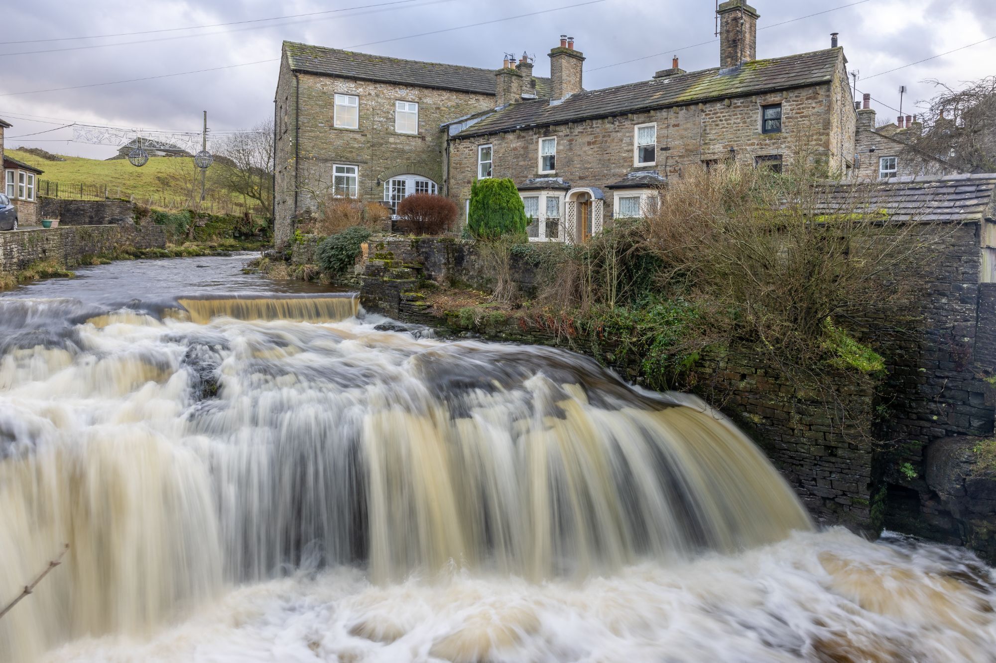 A stone building with a waterfall in front.