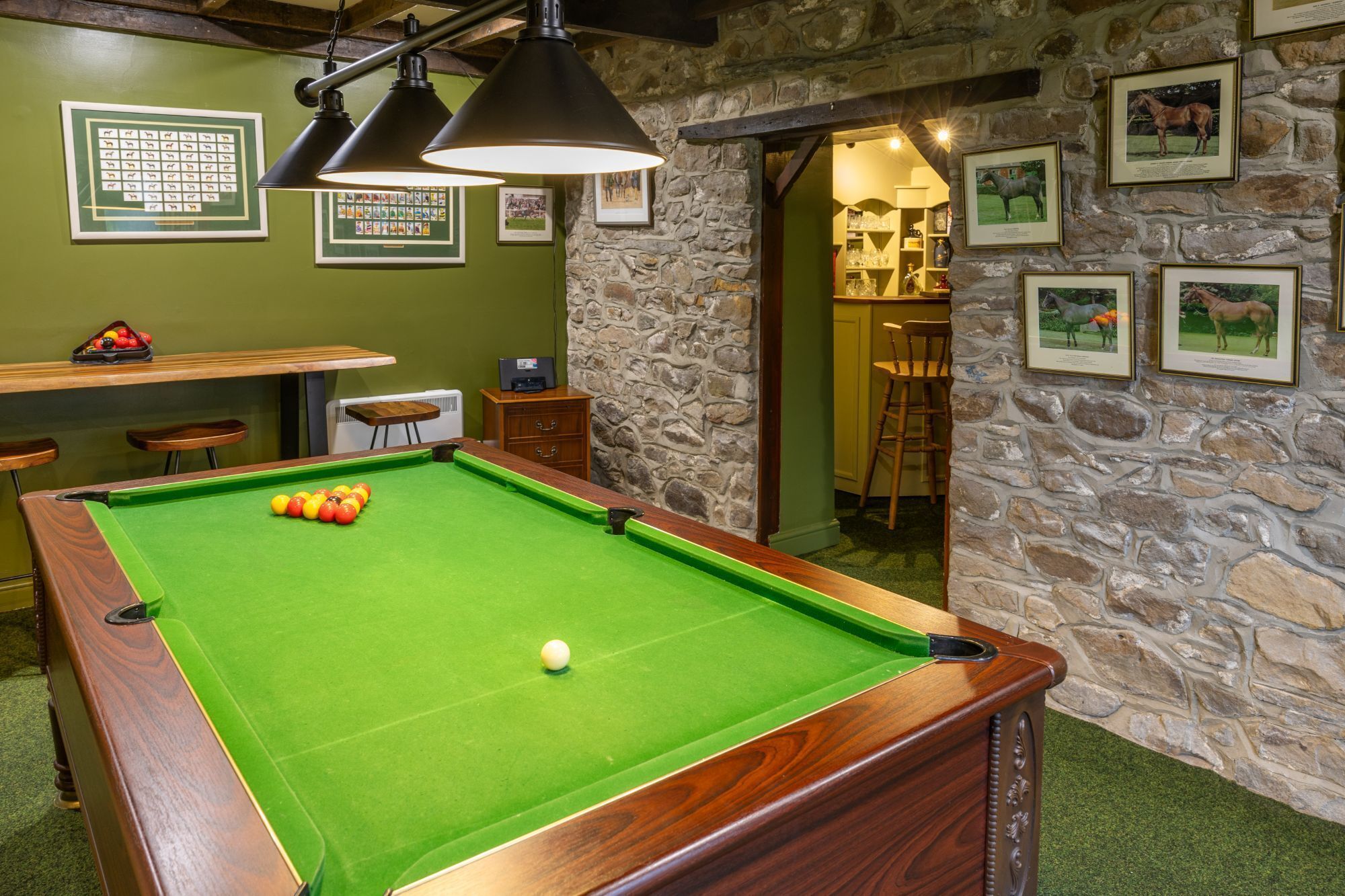 A pool table with balls, a billiard cue, and a framed picture on the wall.