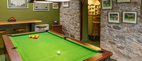A pool table with balls, a billiard cue, and a framed picture on the wall.