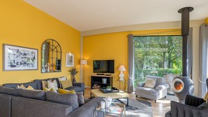 A modern living room with a sofa, armchairs, a glass coffee table, and a fireplace.