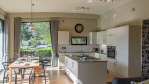 A modern kitchen with a central island, a dining area with a table and chairs, and a view of the outdoors.