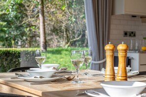 Une table à manger est dressée avec de l’assiette blanche, des bols et des verres à vin, et deux salinières en bois sont posées sur le côté droit.
