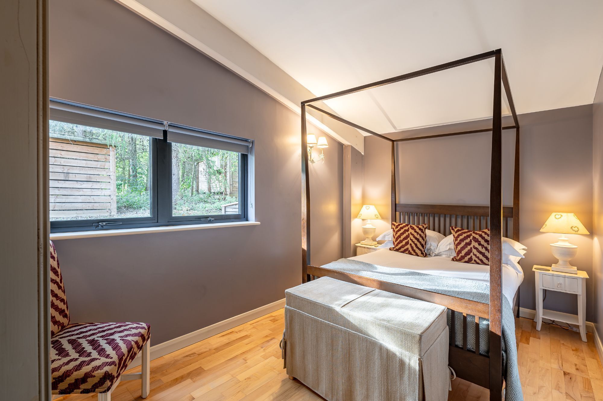 Elegant four poster double bedroom with soft lighting in Jules Lodge at Brompton Lakes, North Yorkshire.