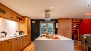 A modern kitchen with wooden cabinets, a central island, and a view of greenery outside. - Georgia -  a cottage that sleeps 6 guests  in 3 bedrooms (Richmond)