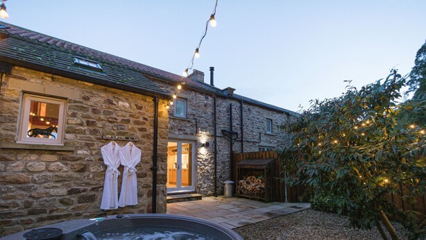 A stone building with a hot tub, a wooden deck, and string lights. - Georgia -  a cottage that sleeps 6 guests  in 3 bedrooms (Richmond)