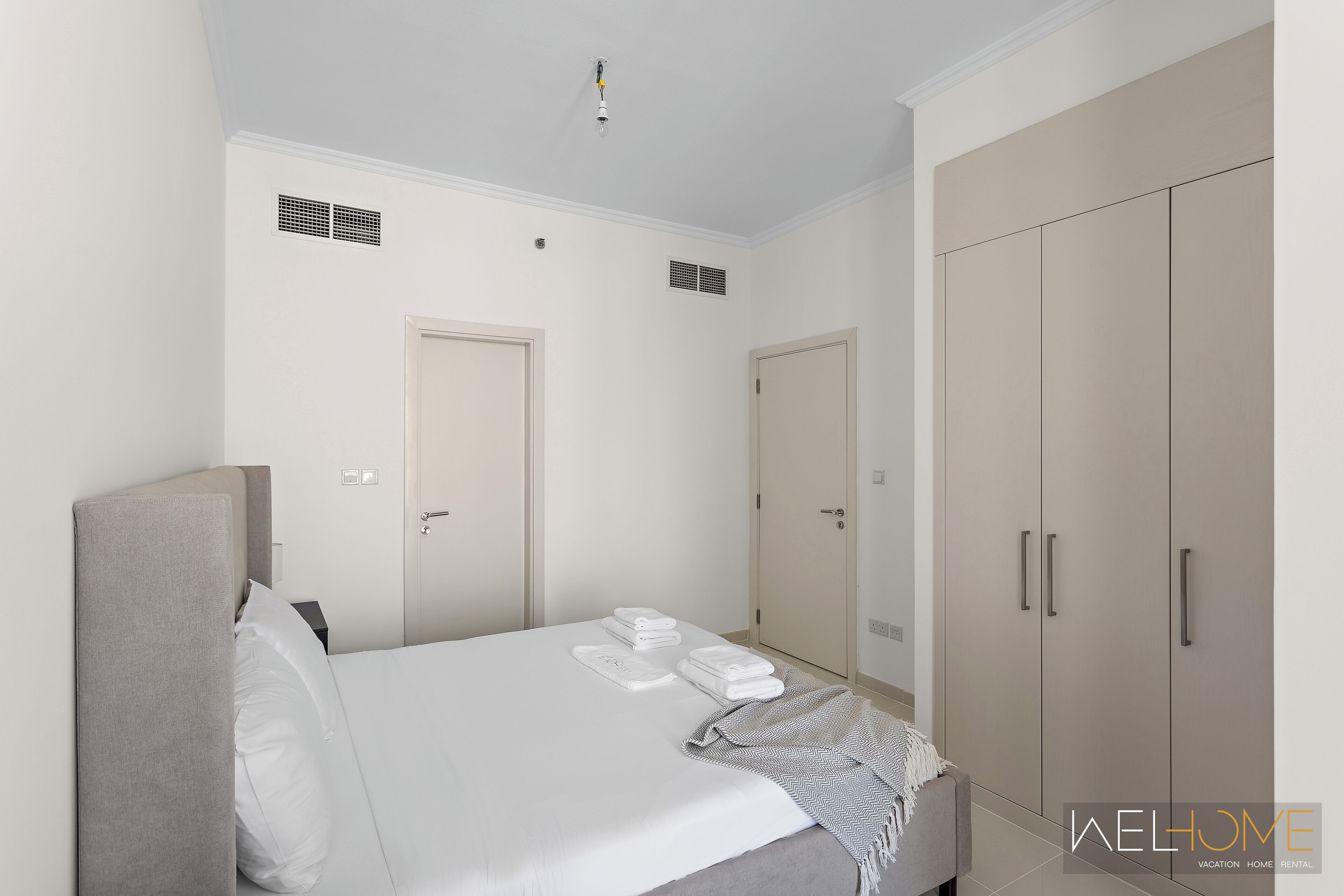 A hotel room with a bed, a wardrobe, and a bathroom door.