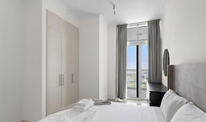 Ein modernes Hotelzimmer mit einem großen Bett, einem Kleiderschrank, einem Schreibtisch und Blick auf die Stadt.