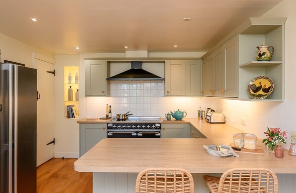 A modern kitchen with a central island, built-in oven, and a stainless steel refrigerator.