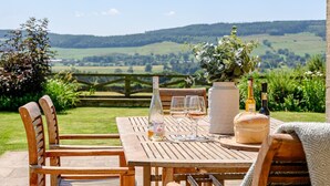 A wooden table with chairs, a vase with flowers, and bottles of wine. - Hollins Farmhouse -  a house that sleeps 10 guests  in 5 bedrooms (Leyburn)