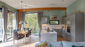 Una cocina moderna con una isla central, zona de comedor con sillas y una sala de estar con sofá.