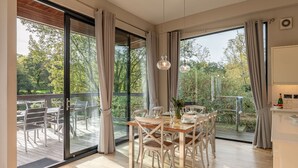 A spacious dining area with a wooden table and chairs, large windows with curtains, and a view of a garden and trees. - Finley -  a lodge that sleeps 6 guests  in 3 bedrooms (Richmond)