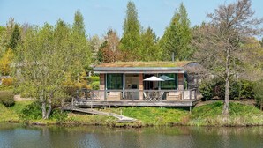 A modern house with a glass facade, a deck, and a pond in front. - Finley -  a lodge that sleeps 6 guests  in 3 bedrooms (Richmond)