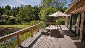 A wooden deck with outdoor furniture, a glass door, and a pond. - Lola -  a lodge that sleeps 6 guests  in 3 bedrooms (Richmond)