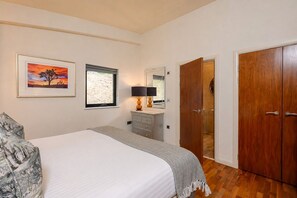 A bedroom with a bed, a dresser, a mirror, and a wardrobe.