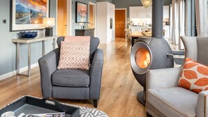 A modern living room with a fireplace, a dining area, and a kitchen in the background. - Lola -  a lodge that sleeps 6 guests  in 3 bedrooms (Richmond)