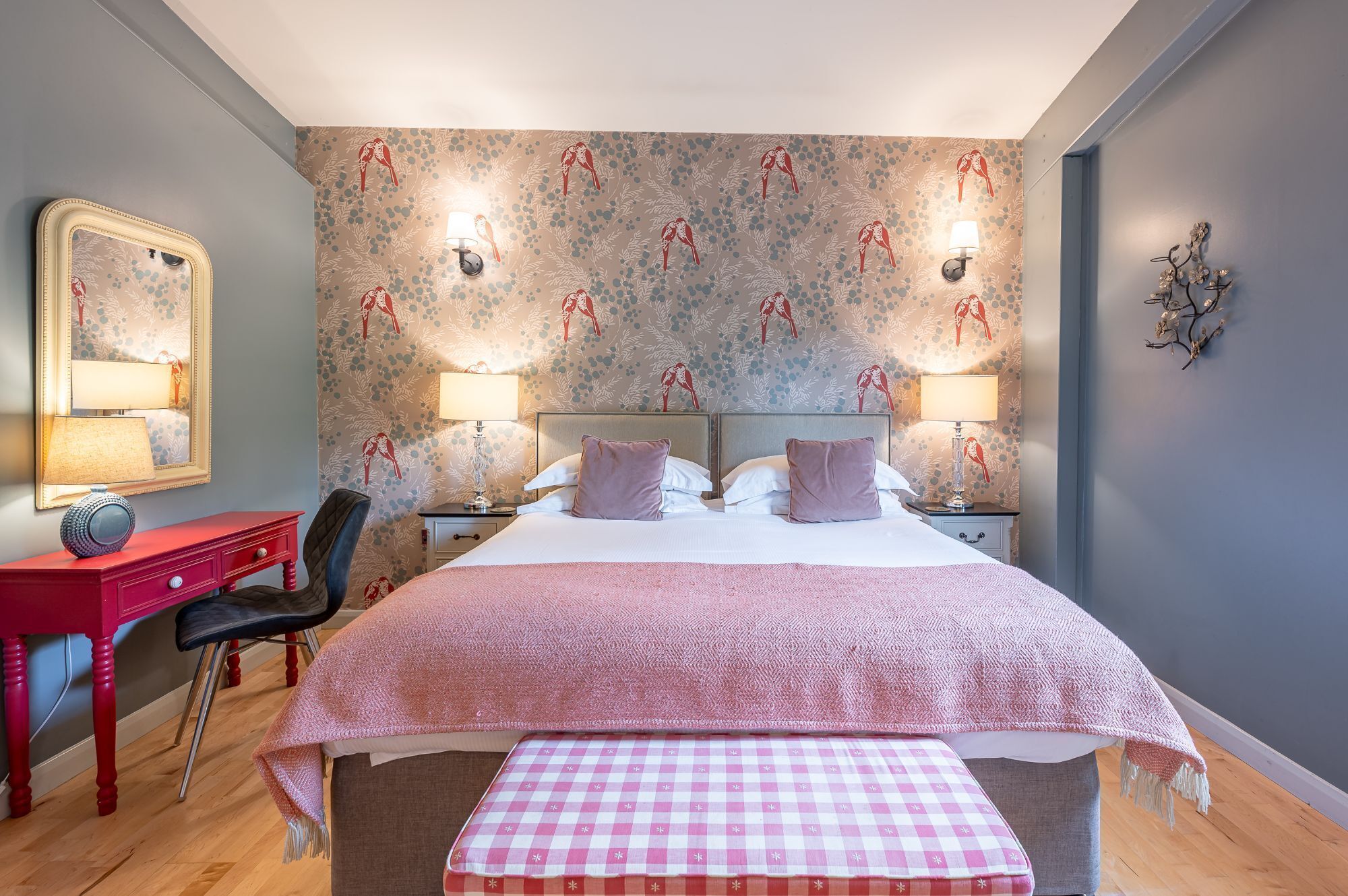 A neatly arranged bedroom with a bed, bedside tables, a chair, and a dresser.