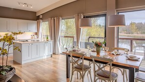 Una cocina moderna con armarios blancos, una isla de madera y un comedor con una mesa dispuesta para cuatro.