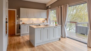 Una cocina moderna con una isla central, armarios blancos y un amplio ventanal con cortinas.