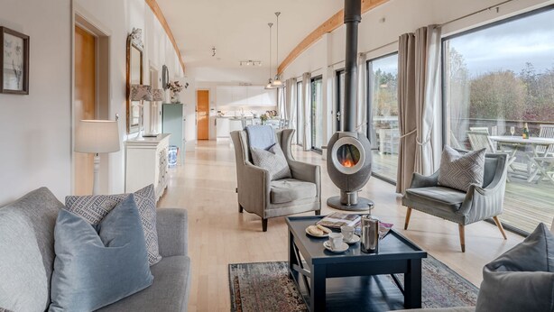 A spacious living room with a modern fireplace, comfortable seating, and a view of the outdoors. - Lulu -  a lodge that sleeps 6 guests  in 3 bedrooms (Near Richmond)