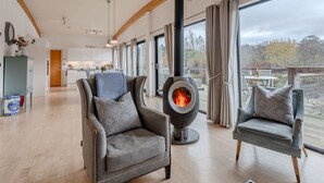 A spacious living area with a modern fireplace, comfortable seating, and large windows offering a view of the outdoors. - Lulu -  a lodge that sleeps 6 guests  in 3 bedrooms (Near Richmond)