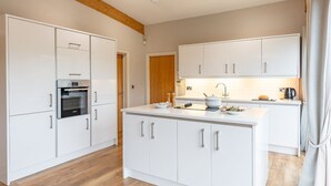 A modern kitchen with white cabinetry, a central island, and a built-in oven. - Charlie -  a lodge that sleeps 6 guests  in 3 bedrooms (Richmond)