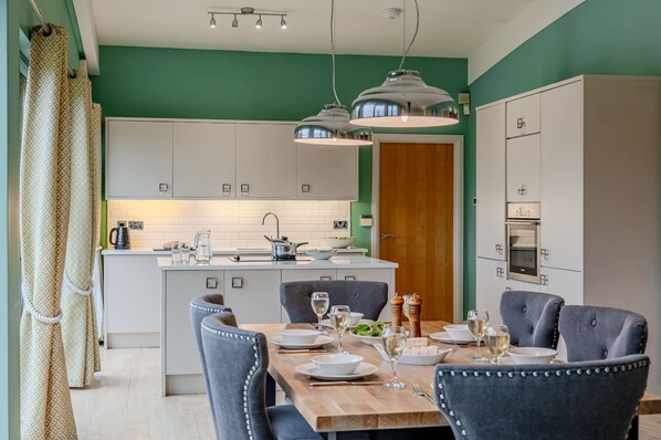 A modern kitchen with white cabinets, a central island, and pendant lighting.