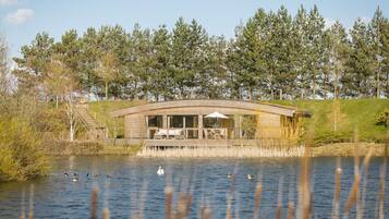 Een vakantiehuis aan het meer met een overdekt terras en uitzicht op het omliggende bos.