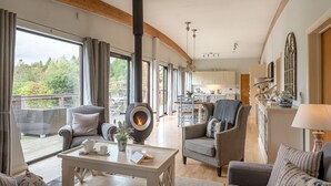 A cozy living room with a fireplace, large windows, and a view of the outdoors.