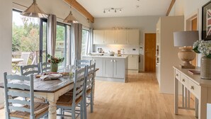 A modern kitchen with wooden beams, a central island, and a dining area with a table and chairs.