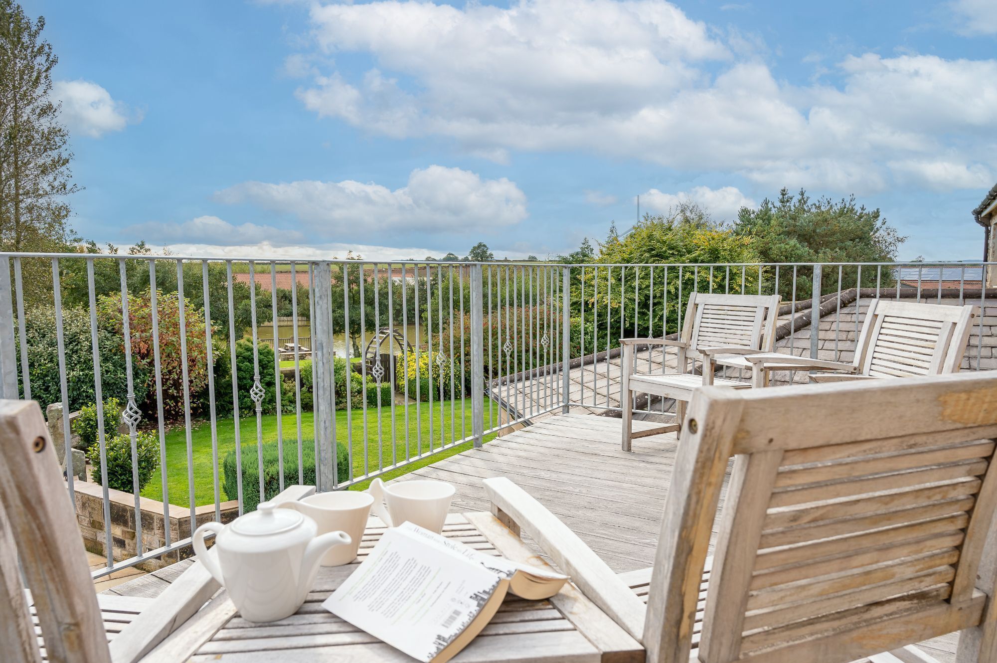 A wooden deck with outdoor seating and a view of a garden and water feature.