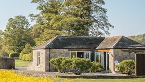 Une petite maison en pierre avec un toit en pente, une porte d’entrée et un petit porche.