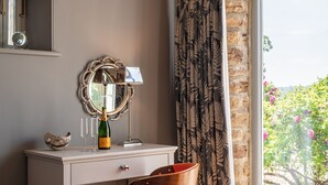 Une pièce comprenant une coiffeuse, un miroir, une bouteille de champagne, deux verres et un bol décoratif.