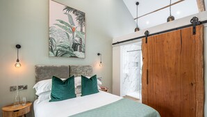 Ein Schlafzimmer mit einem Bett, grünen Kissen, einem großen Gemälde und einem Holzschrank.